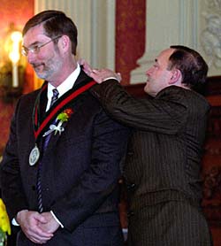 At an installation ceremony March 16 in Holmes Lounge, Chancellor Mark S. Wrighton places a medallion around the neck of Thomas F. Oltmanns, Ph.D., signifying him as the holder of the Edgar James Swift Professorship in Arts & Sciences. Oltmanns is a leading researcher on the cognitive and emotional factors behind personality disorders. Swift founded the University's first stand-alone psychology department in 1924.