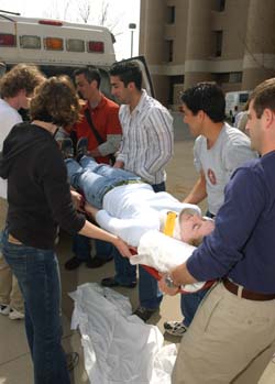 (Clockwise, from front left) First-year medical students Megan Denzel, Kevin Alford, Seth Stalcup, Paymon Rahgozar and Derek Williams work with Mark D. Levine, M.D., on the team approach to properly lifting and loading fellow first-year student and 