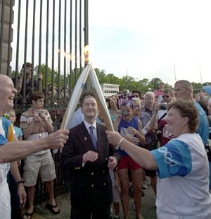 St. Louis philanthropist E. Desmond Lee is all smiles as he lights the torch of Teri Clemens, who coached the Washington University volleyball Bears to seven national titles, including six straight from 1991-96. Wrighton is framed by the torches.