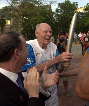 A jubilant E. Desmond Lee finishes off his run around Bushyhead Track in Francis Field. Washington University Chancellor Mark S. Wrighton (foreground, left) congratulates Lee on his run.