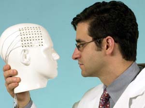 Eric C. Leuthardt, M.D., examines an electronic grid that can be placed atop the brain to gather motor signals that enable patients to play a computer game by only using their brains. The breakthrough is a step toward creating biomedical devices that can control artificial limbs.