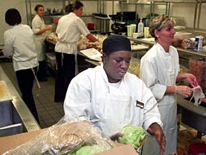 Juanita Bobo, pantry cook for Bon Appetit, chops lettuce in the Wohl Student Center kitchen as the staff prepares for another day's food distribution.