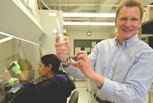 Lars Angenent holds a biosampler while postdoctoral researcher Bala Ramaswami works behind him.  Angenent and a team of researchers used a molecular technique to identify a bioaerosol that made lifeguards working at a hot water therapy pool ill.