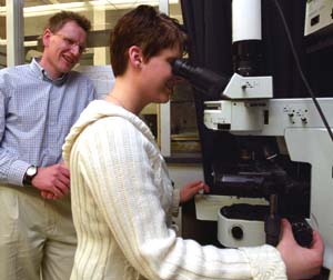 Lars Angenent guides graduate student Rebecca Hoffman as she examines bacteria from air digesters under a high-powered epifluorescence microscope.