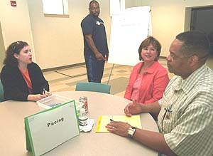 Webster Groves Hixson Middle School mathematics teachers Ferrell Roddy (right) and Randy Taylor (standing) discuss pacing students through an entire year of a special mathematics program called the Connected Math Program (CMP) with Francis Howell Middle School mathematics teacher Melissa Lenger (left) and Victoria May, WUSTL director of science outreach. Middle-school mathematics teachers worked with May and other science outreach personnel on mathematics curriculum strategies in a series of focus discussions. May said the goal is to establish a regional network of teachers to promote dialog and focus on increased rigor in implementing the CMP curriculum.