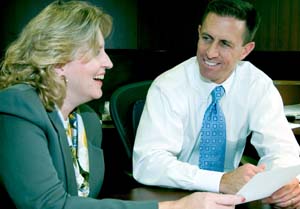 Mark W. Eggert, J.D., associate vice chancellor and deputy general counsel, talks with Lisa M. Braun, J.D., associate general counsel, in his office in the East Building on the Medical Campus. Says Michael Cannon, J.D., executive vice chancellor and general counsel,