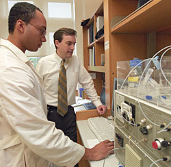 Donald Elbert (right) working with his graduate student Evan Scott at the optical waveguide light spectroscope to observe proteins sticking to a polymer surface in their Whitaker Building laboratory.