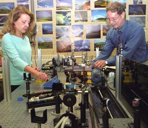 Christine Kirmaier (left) and Dewey Holten making adjustments in their sophisticated laser laboratory in Louderman Hall . The husband-wife team have tricked electrons to choose another path in a bacteria's reaction center protein, the factory for photo