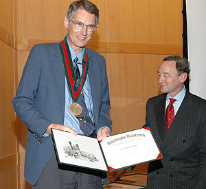 Jonathan S. Turner, Ph.D., (left) receives the Barbara J. and Jerome R. Cox Jr. Professor of Computer Science medal and a certificate from Chancellor Mark S. Wrighton. The professorship was established to advance the relationship between theory and practice in the design of digital systems.