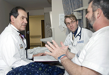 (From left) Alex Denes, M.D., and John Welch, M.D., Ph.D., a fellow in hematology/oncology, visit with patient Richard Wall at Barnes-Jewish Hospital.