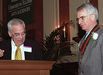 Edward S. Macias, Ph.D. (left), congratulates Costas Azariadis, Ph.D., on being named an Edward Mallinckrodt Distinguished University Professor at the installation ceremony Feb. 1 in Holmes Lounge.