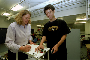 Shirley Dyke (left) and Pengcheng Wang  adjust wireless sensors onto a model laboratory building in Dyke's laboratory.  Dyke is the first person  to test wireles sensors in  simulated structural control experiments  She envisions  a wireless future for structural control technology.