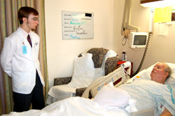 Tyler Merchant talks with Noel Tate, who is recovering after heart surgery. Merchant participates in WU's Health Care Advocacy Program.