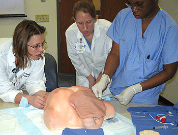 (From left) Julie Margenthaler, M.D.; Elizabeth Fialkowski, M.D., a surgical resident; and Lola Fayanju, a fourth-year medical student, practice installing a central line, used to give treatments such as chemotherapy, antibiotics and intravenous fluids and feeding, into a simulated patient during one of the labs in the Accelerated Skills Preparation for Surgical Internship course.