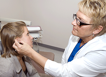 Ann Vitale adjusts Emily Gravenhorst's prosthetic ear in the School of Medicine's maxillofacial prosthetics laboratory.