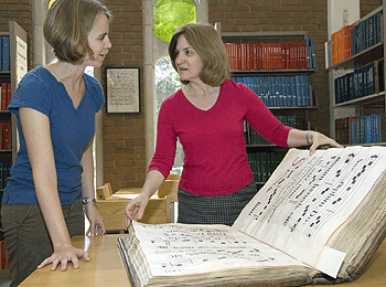 In the Gaylord Music Library, Dolores Pesce, Ph.D. (right), and doctoral student Sarah Ruddy examine an 18th-century chant manuscript that was donated to Washington University Libraries. Pesce says that she and other music faculty members use such documents to train students to identify manuscripts and determine where and when they were written and for what purpose.