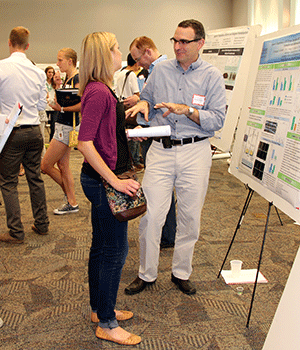 Graduate student Allyson Mayer visits with Carlos Bernal-Mizrachi, MD, assistant professor of medicine and of cell biology and physiology, at the Division of Biology and Biomedical Sciences poster presentation event in August.