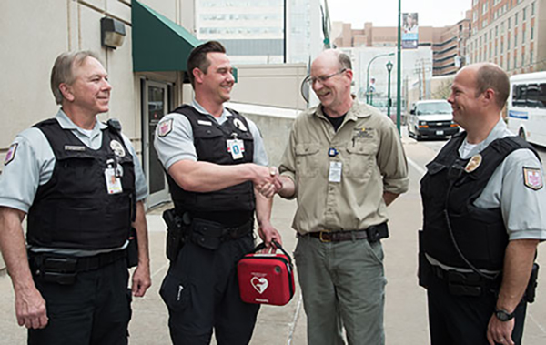 Barnes-Jewish Hospital employee John VanderHeyden (khaki shirt) meets Washington University School of Medicine security officers (from left) Robert Brooks, Mark Mallow and (far right) Scott Johnson. Brooks, Mallow and Johnson used an automated external defibrillator to revive VanderHeyden after he collapsed Dec. 3 in a parking lot on the Medical Campus.  Photo: Robert Boston