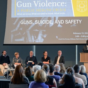 man at podium leading panel on guns and suicide