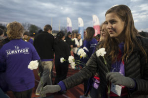 student hands flowers to cancer survivors