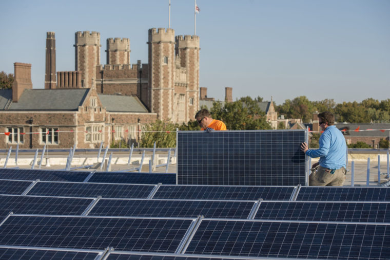 Workers installing solar panels on Hillman Hall.