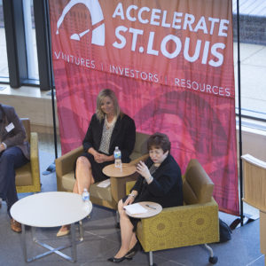 three people in chairs chatting on a stage