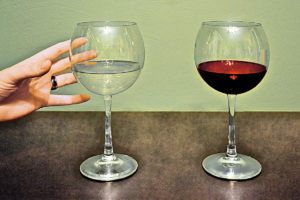 A hand reaching for two glasses of wine.