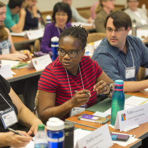 three faculty members chat in a classroom