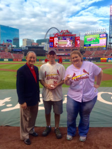 people pose with baseballs on the field at Busch Stadium