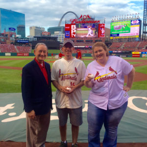 people pose with baseballs on the field at Busch Stadium