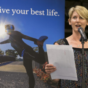 woman speaks in front of fitness banner