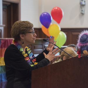 Feldbum speaks in front of rainbow banner