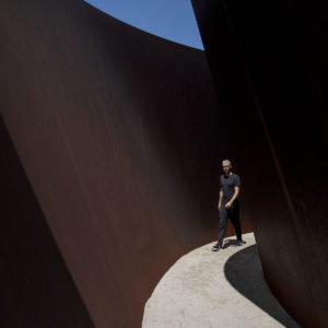 a man walks through a curved outdoor corridor