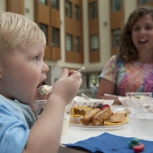 a little boy puts a spoonful of vanilla ice cream into his mouth.