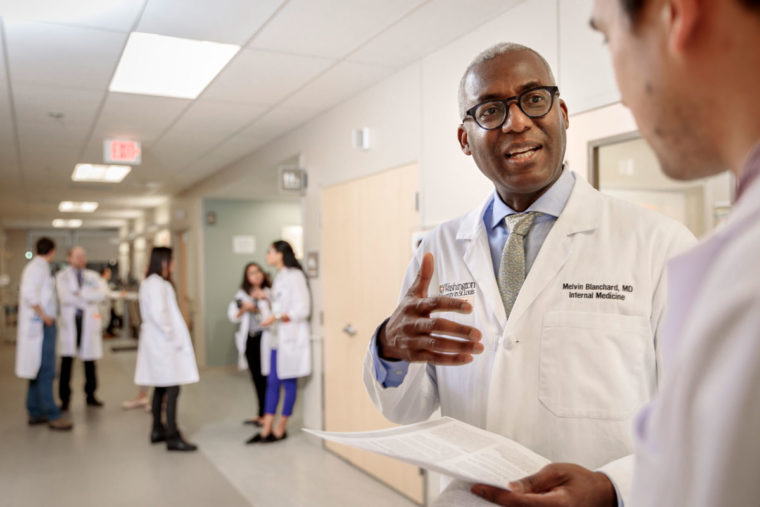 Melvin Blanchard, MD, talks with Andrew Young, MD, PhD, at the Center for Outpatient Health