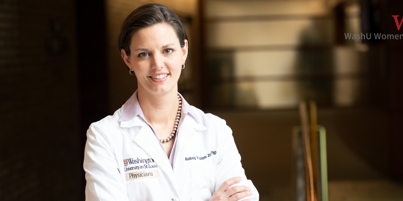 Physician and researcher Dr. Audrey stands with her arms crossed wearing a white lab coat emblazoned with the logo of the Washington University School of Medicine in St. Louis