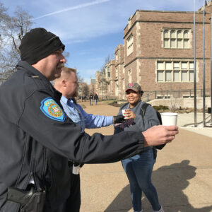 Police officers passing out hot cocoa