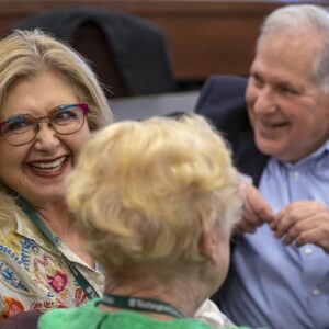 Two women and one man smiling and chatting.