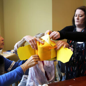 Three teacher hold object made of with felt, string and pipe cleaners.