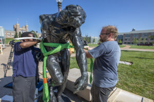 two men install sculpture outside