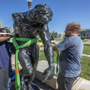 two men install sculpture outside