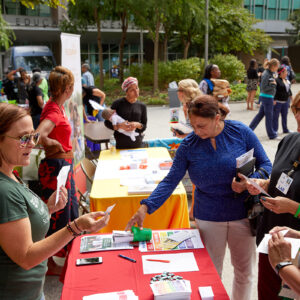 Erin Stamp stands behind a table and talks to people at the Diversity Fair.