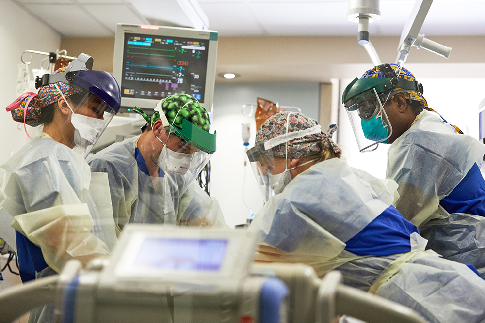 In May, frontline caregivers are treating a COVID-19 patient in an intensive-care unit at Barnes-Jewish Hospital. The critical-care team includes nurse Kyle Breitenstein (green cap) and Praveen Chenna, MD (far right), associate professor of medicine in the Division of Pulmonary and Critical Care Medicine. (Photo: Matt Miller/Washington University School of Medicine)