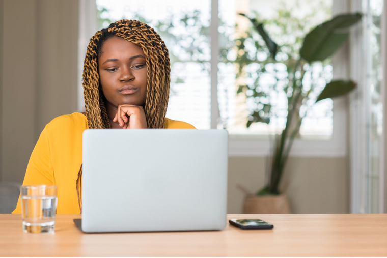 Woman with neutral expression looking at computer monitor