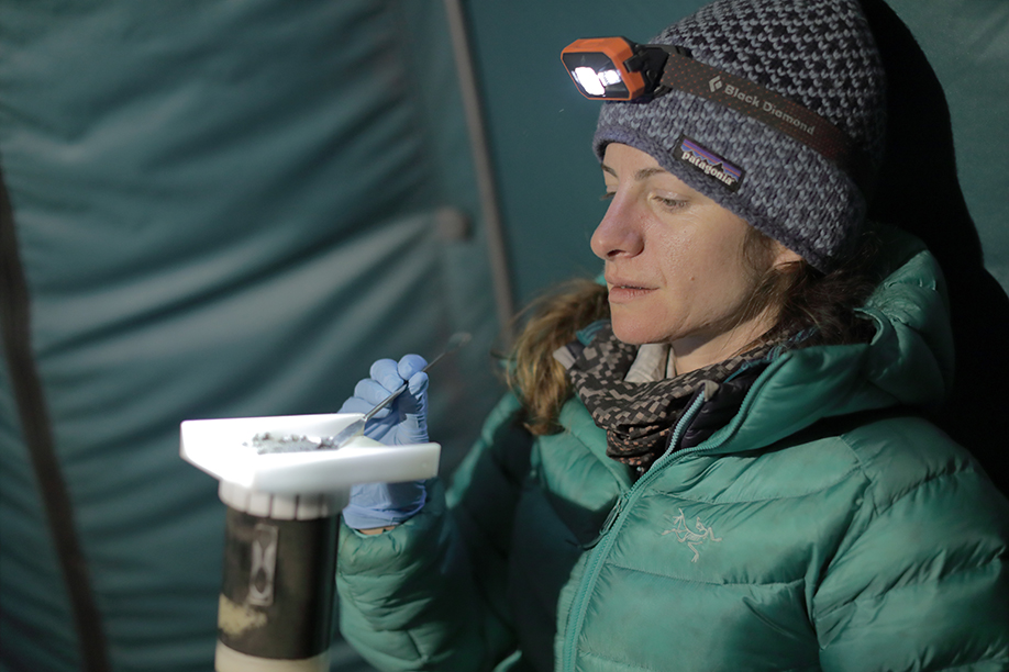 Bronwen Konecky slices sediment collected from the bottom of Lake Sibinacocha to catalog for future study. (Photo: Tom Malkowicz)