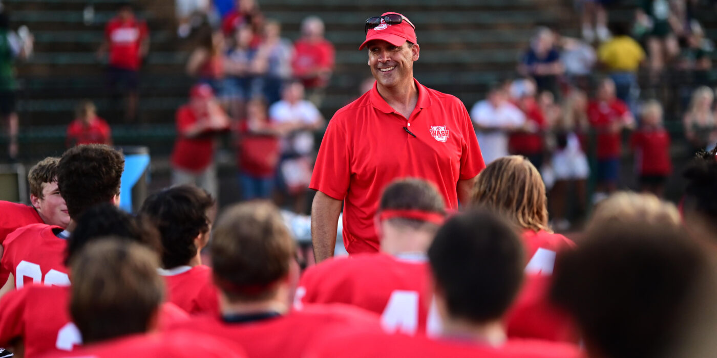 Football coach Aaron Keen and the team celebrate their first win.