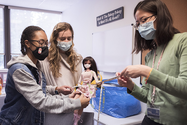 Shelei Pan (right) show model BeLov'ed Noble Creation Brooks the tape measure they will use to collect measurements at a meeting of designers and models Sept. 30. (Photo: Carol Green/Washington University)