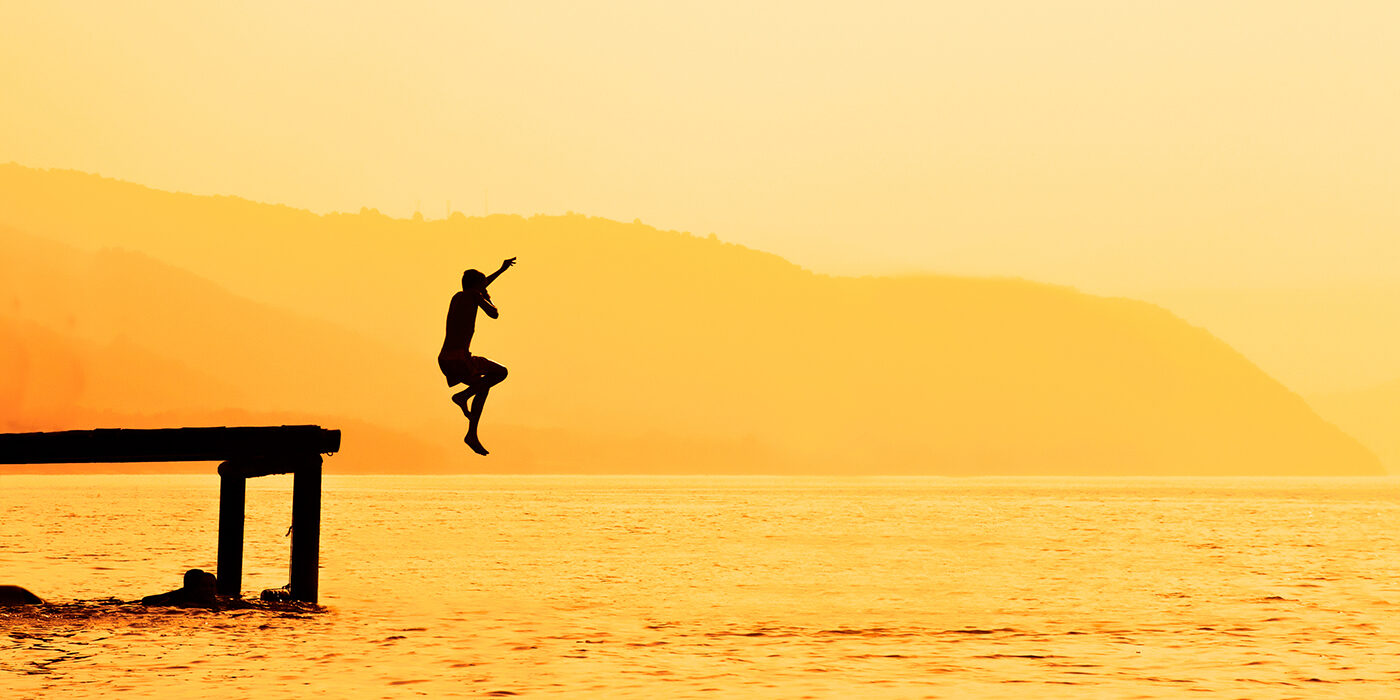 kid jumps into water at sunset