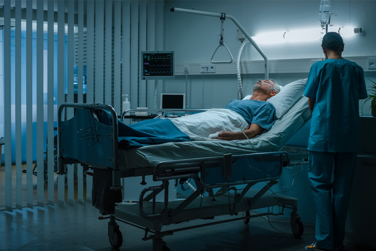 Man in a hospital bed being cared for by a nurse