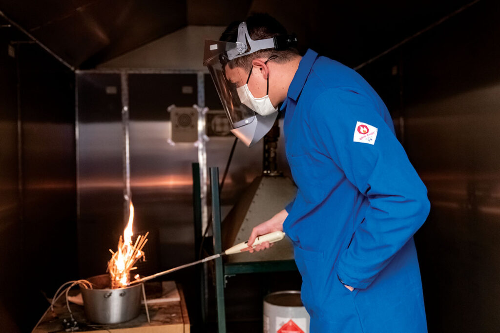 Theo Paik, BSChE ’19, a PhD student in Chakrabarty’s lab, ignites biomass in a combustion chamber. Burning biomass taken directly from places where forest fires burn allows the research team to analyze the properties and life-cycles of the particles emitted by fire. (Photo: Joe Angeles)